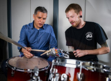 Professor Gil Weinberg and Jason Barnes, wearing prosthesis, seated behind drums