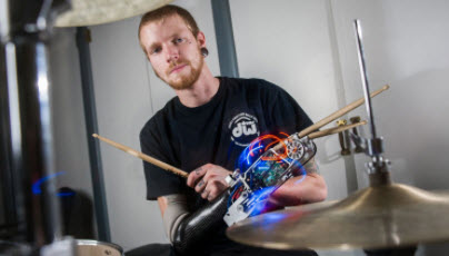 Jason Barnes at drums wearing drumming prosthesis. Cymbals in foreground.